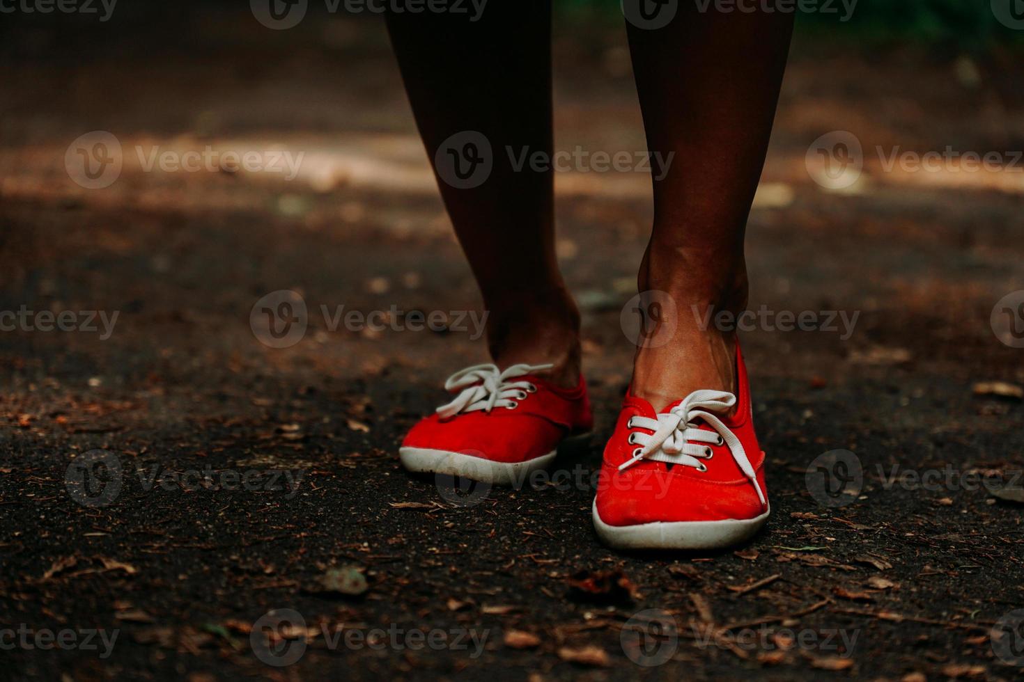 benen in rode sneakers op een herfstpad in het park. zwarte leren poten foto