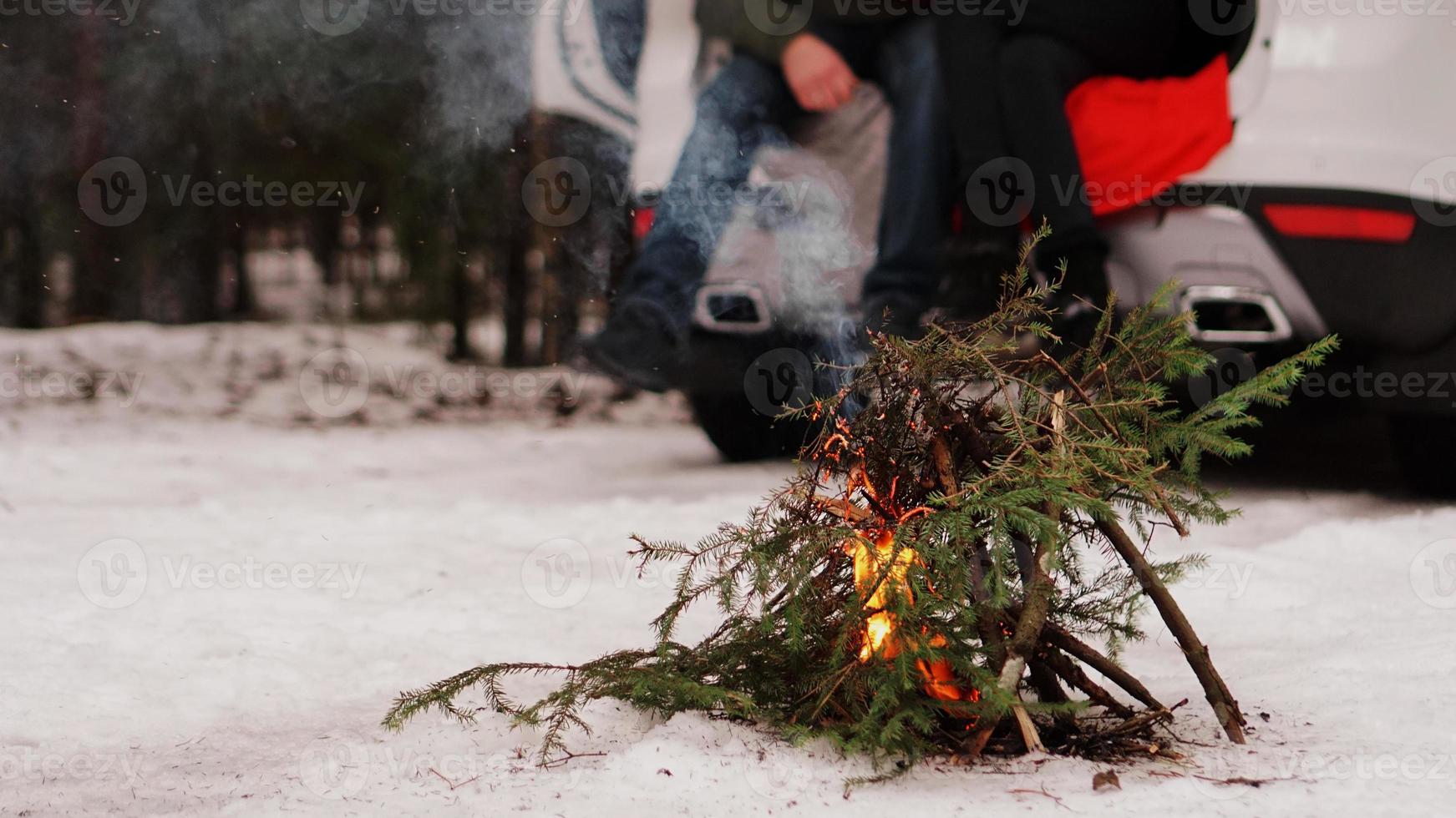 vreugdevuur in het winterbos - koppel in vrachtwagen op onscherpe achtergrond foto