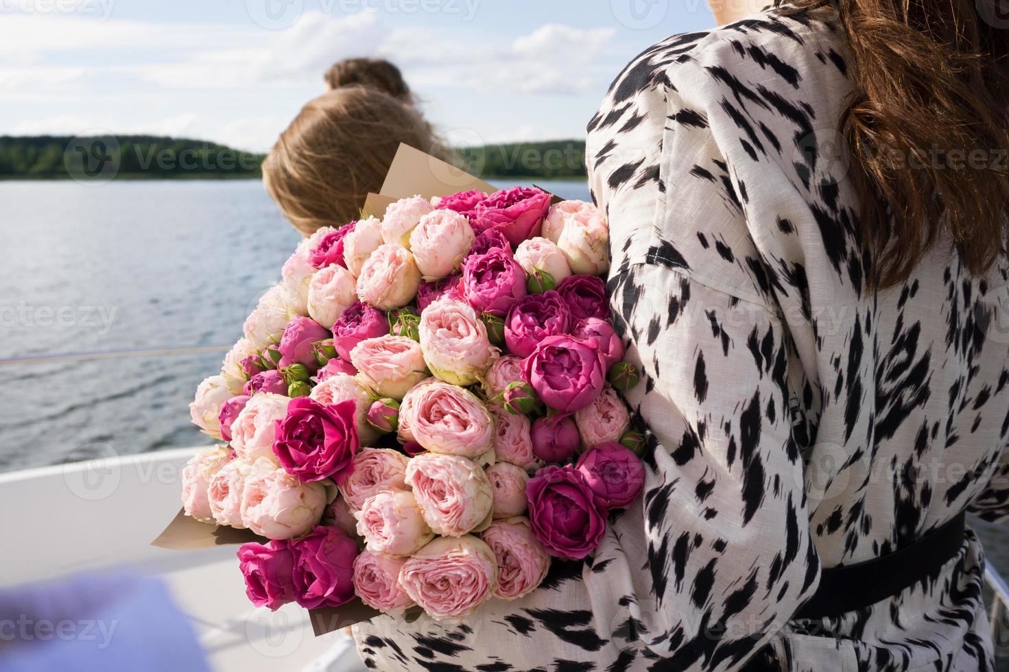een jong meisje met een boeket fleurige bloemen op een cruiseschip foto