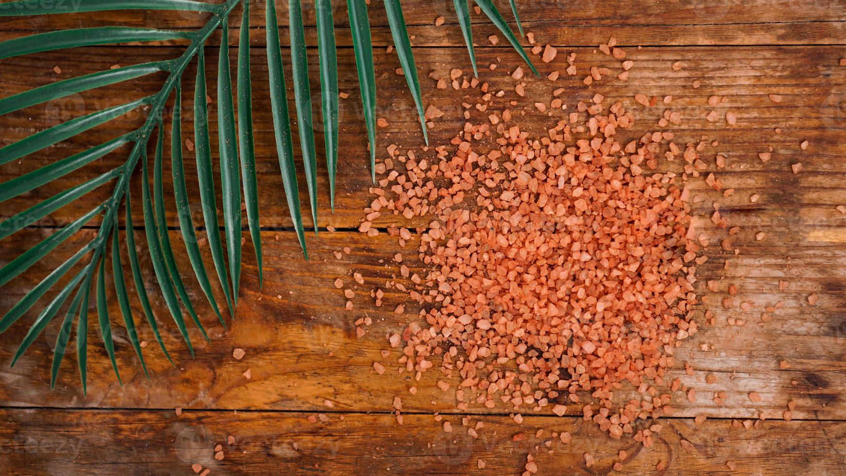 oranje zeezout op een houten ondergrond. tropische palmbladeren foto