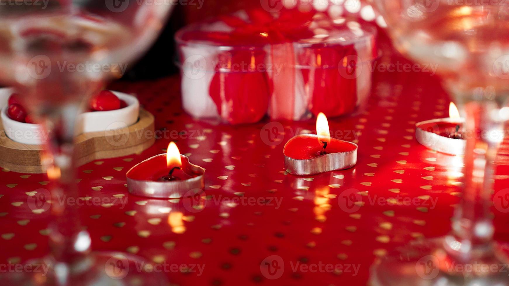kaarsen voor Valentijnsdag, tafel met feestelijke rode achtergrond foto