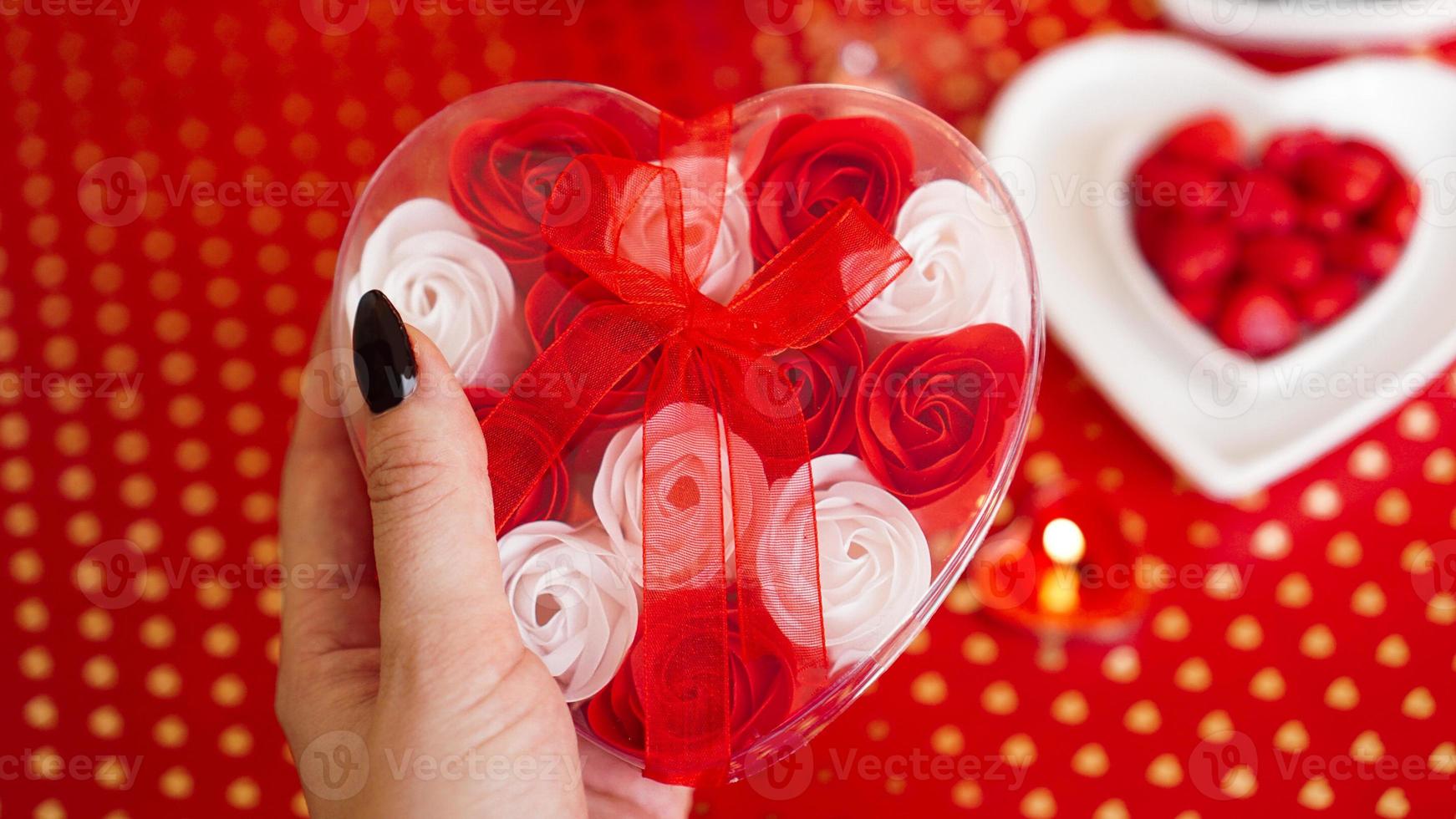 vrouw handen met een geschenkdoos in hartvorm met mooie roos foto