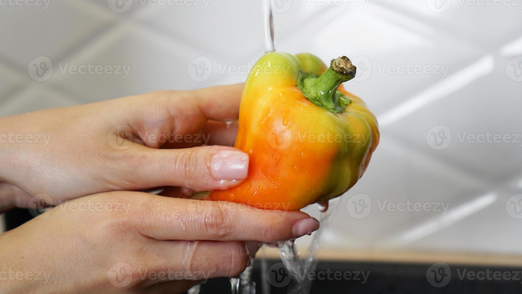 vrouwelijke handen wassen gele en rode kleur peper foto