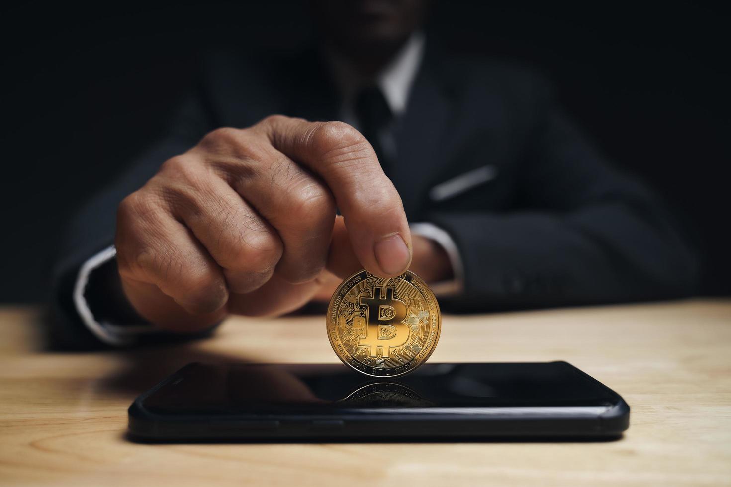 zakenman houdt gouden bitcoin op smartphone vast voor bitcoin-handel. foto