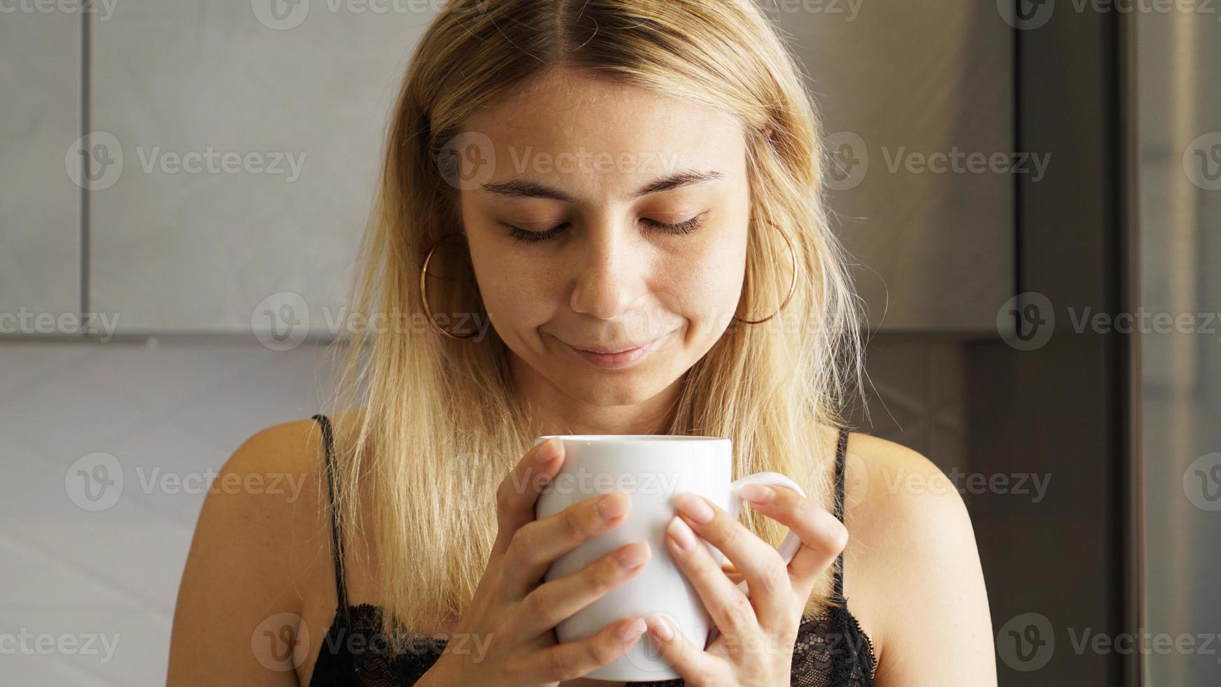 close-up van een vrouw die de geur van koffie inademt met haar ogen dicht foto