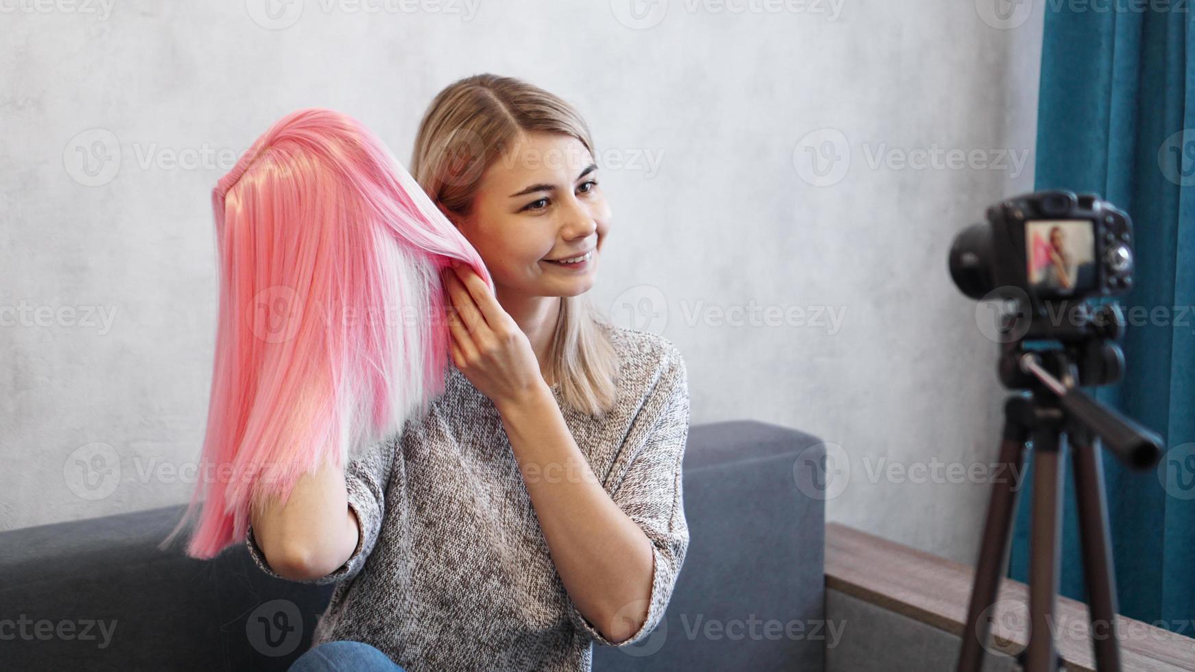 vrouw blogger neemt video op. ze toont roze pruik foto