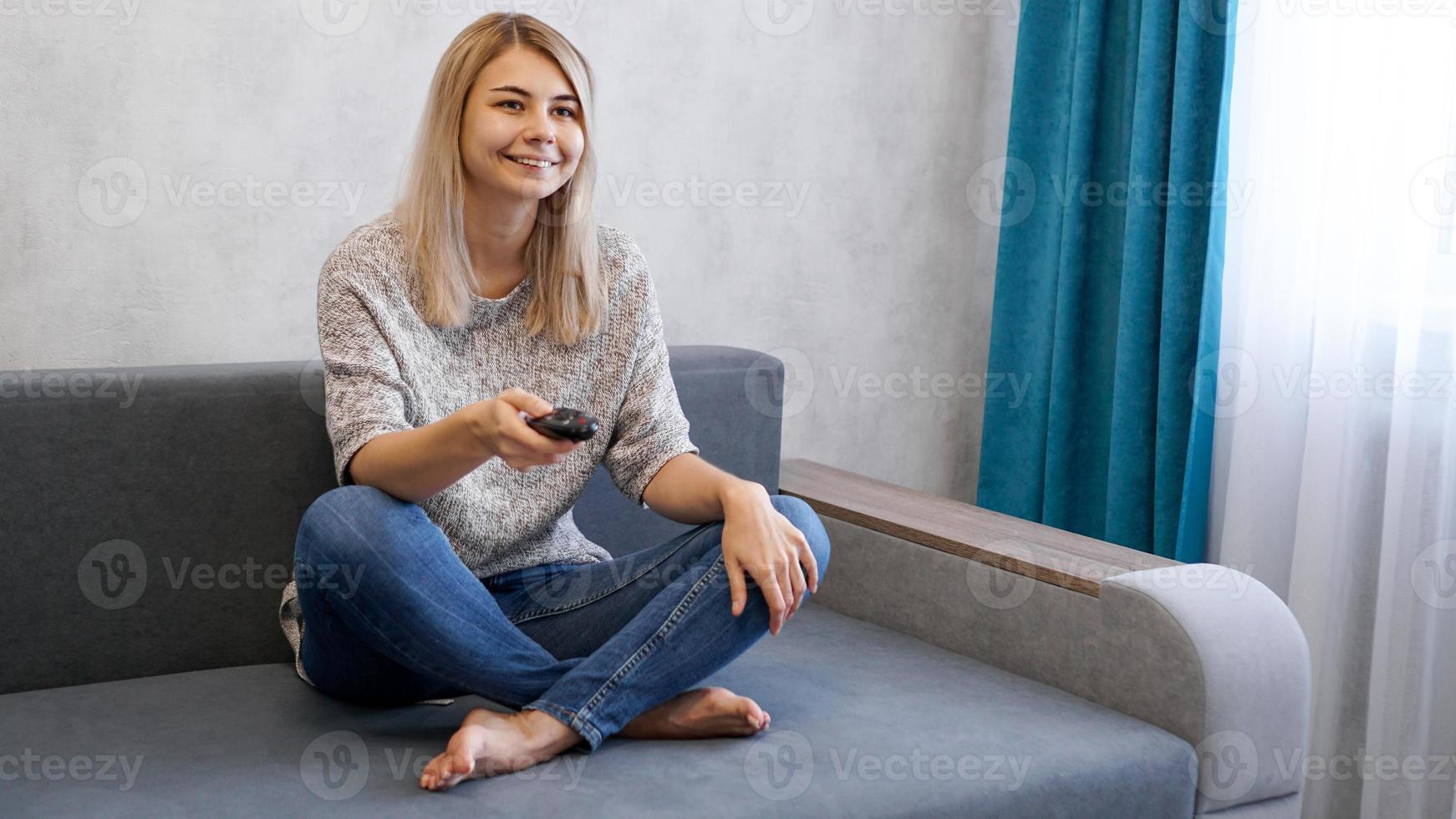 gelukkige vrouw die tv kijkt zittend op een bank in de woonkamer thuis foto