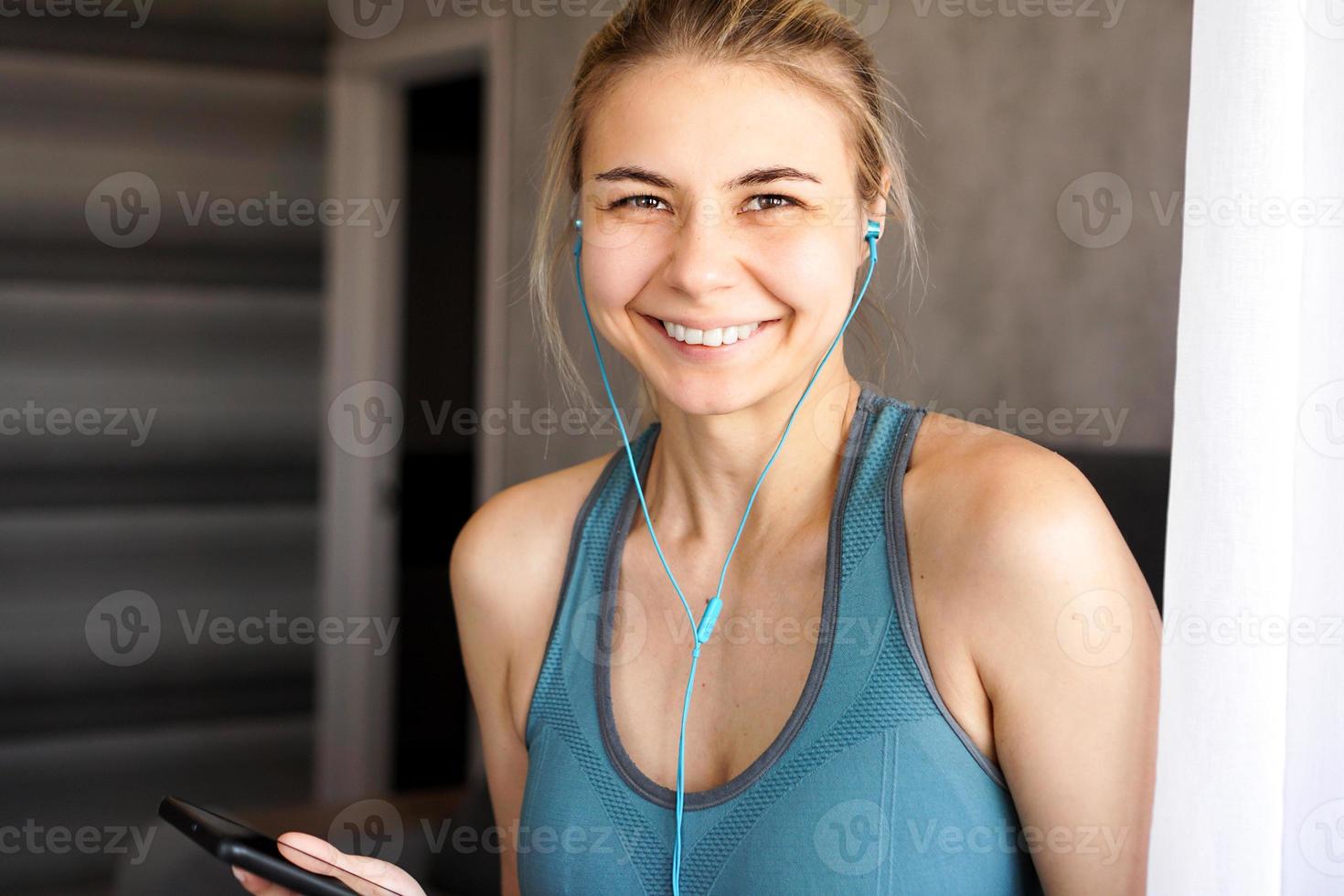 jong vrij sportief meisje thuis luistert naar muziek op een koptelefoon foto