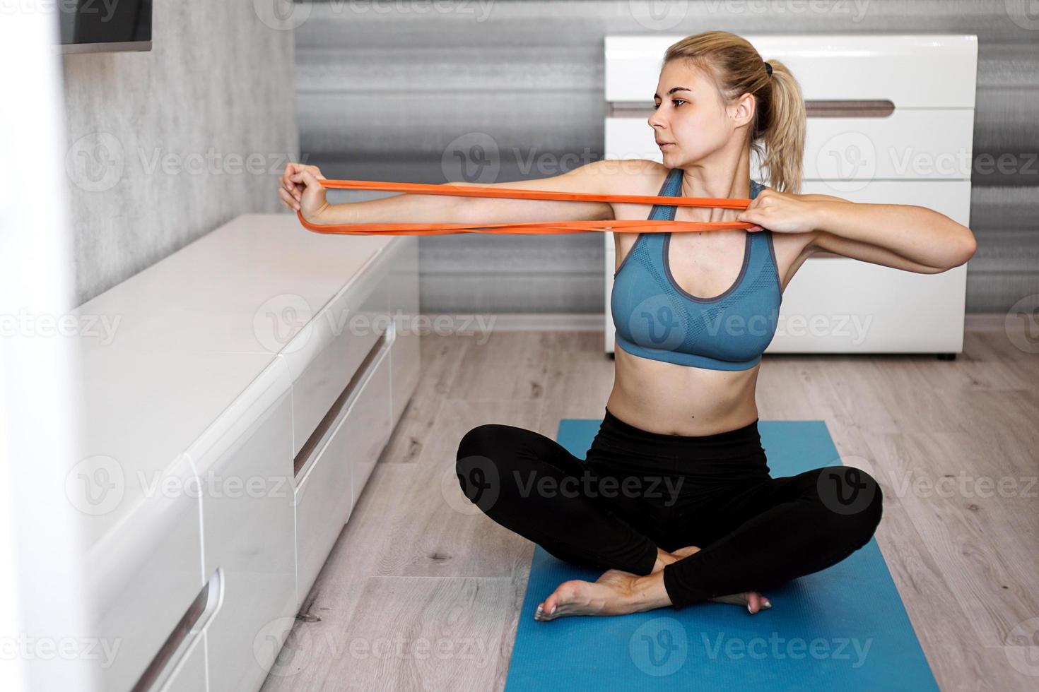 vrouw thuis die probeert af te vallen en te trainen met elastische band foto