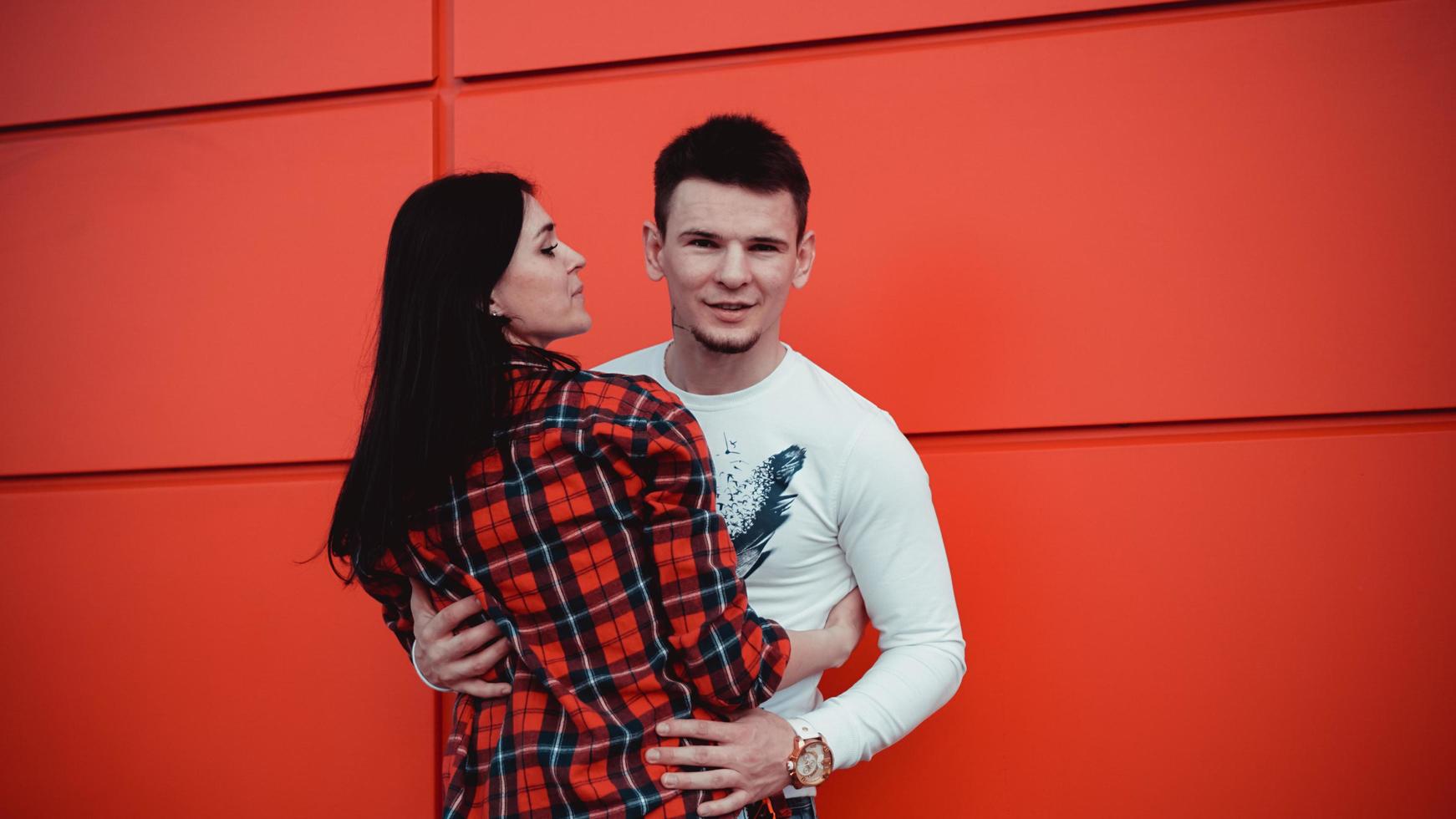 paar daten en verliefd knuffelen op een zonnige dag - rode achtergrond foto