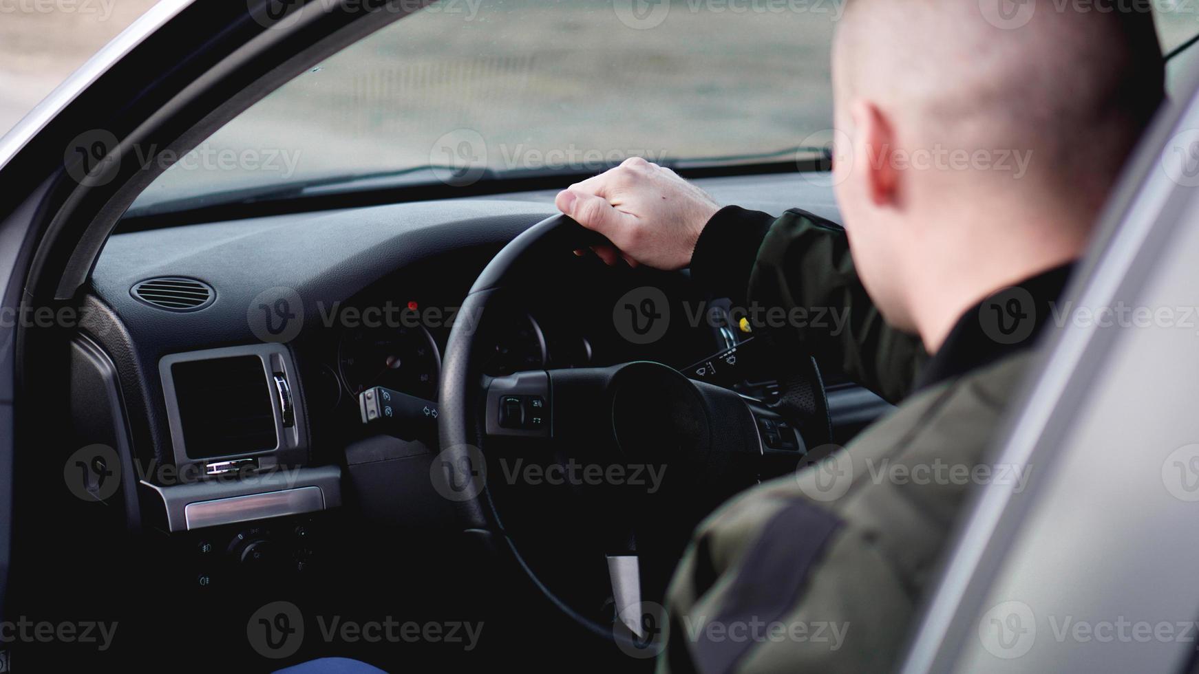 zijaanzicht van zelfverzekerde jonge stijlvolle man in zijn auto foto