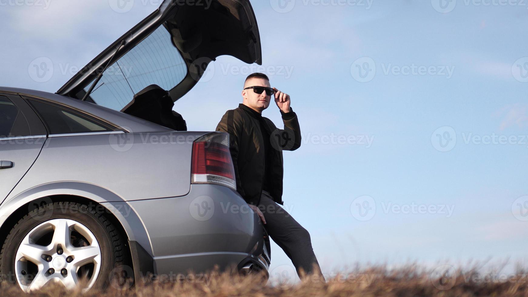 sde weergave van zakenman in bril zittend op auto kofferbak foto