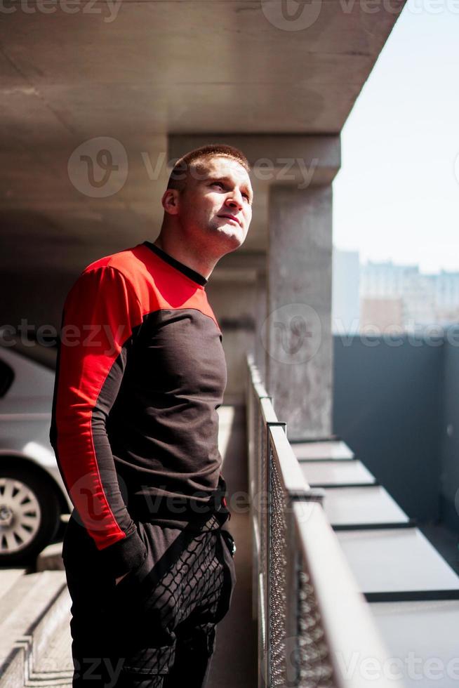 jonge man in sportuniform op de parkeerplaats. uitzicht op de stad foto