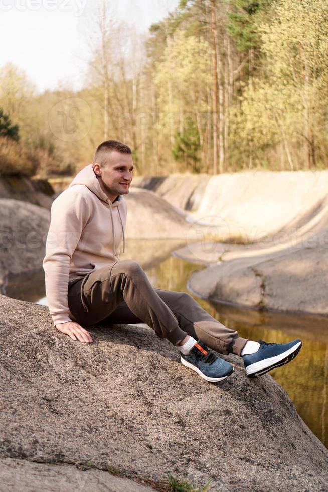 jonge man in een comfortabel pak aan de rand van een roeikanaal foto