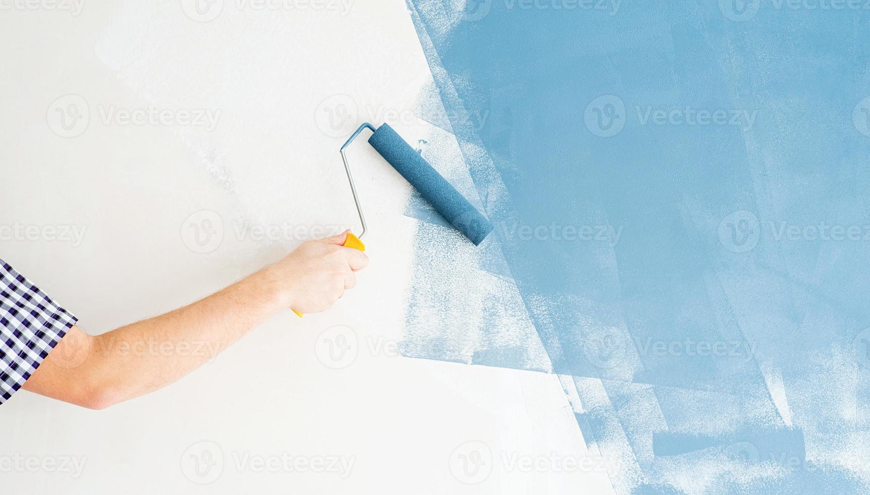 man kleurt muur blauw met een roller foto