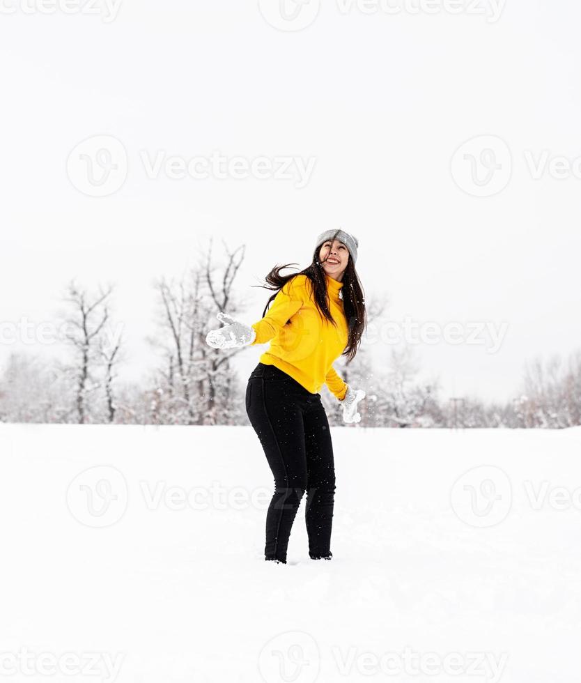 jonge brunette vrouw spelen met sneeuw in park foto