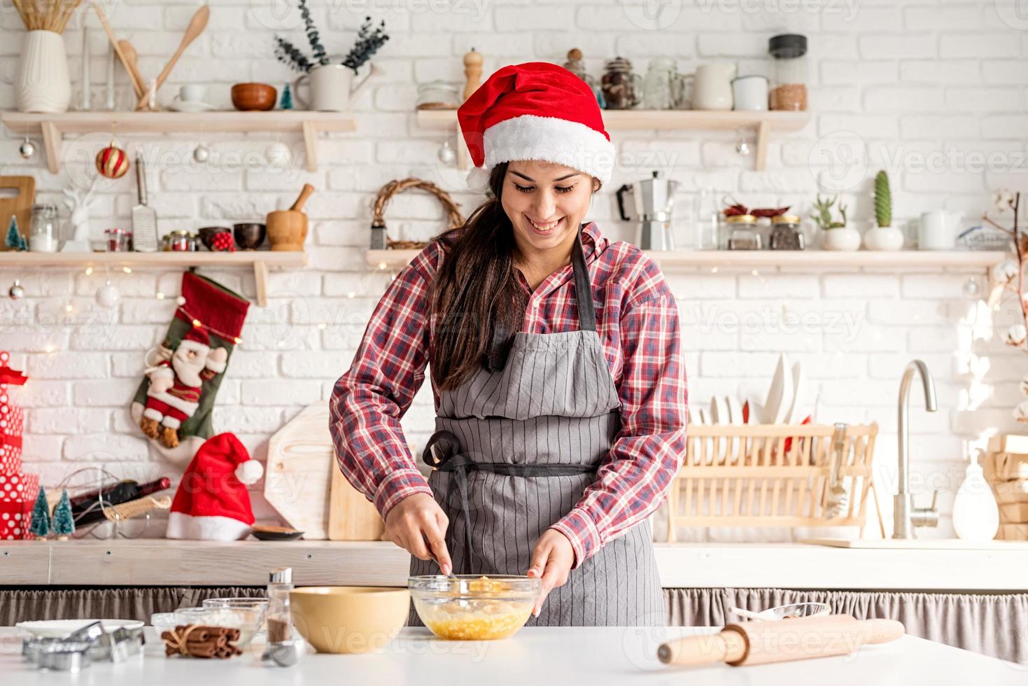 jonge latijnse vrouw die eieren zwaait die in de keuken koken foto