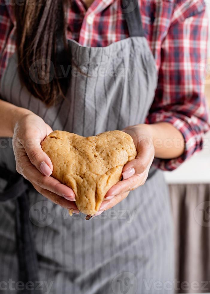 vrouw handen met hartvormig deeg foto