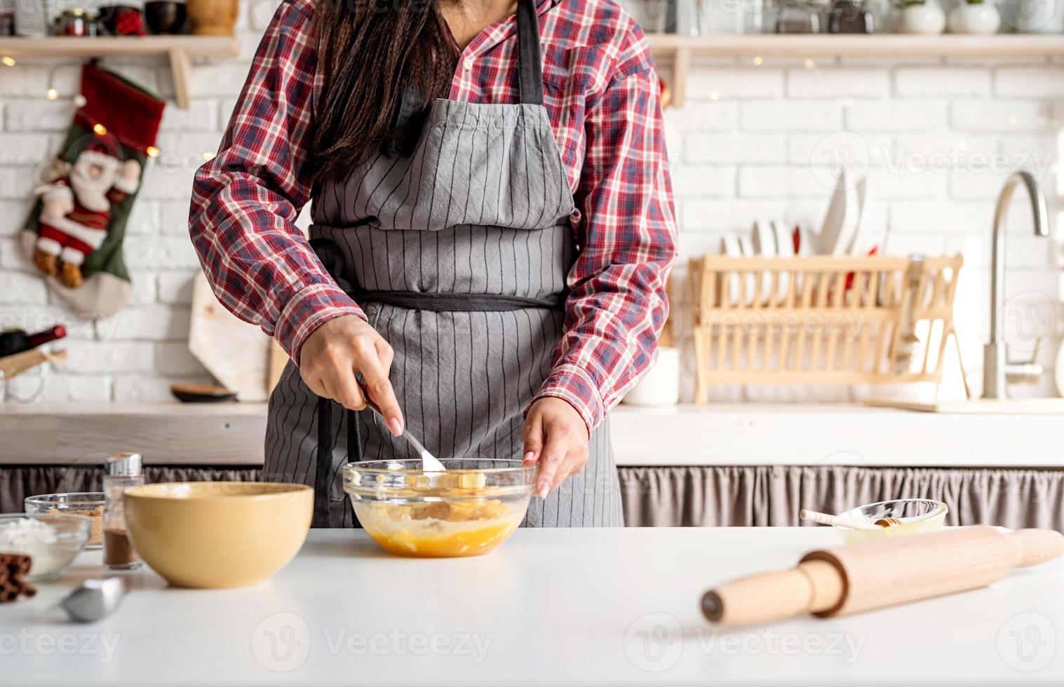 jonge latijnse vrouw die eieren zwaait die in de keuken koken foto