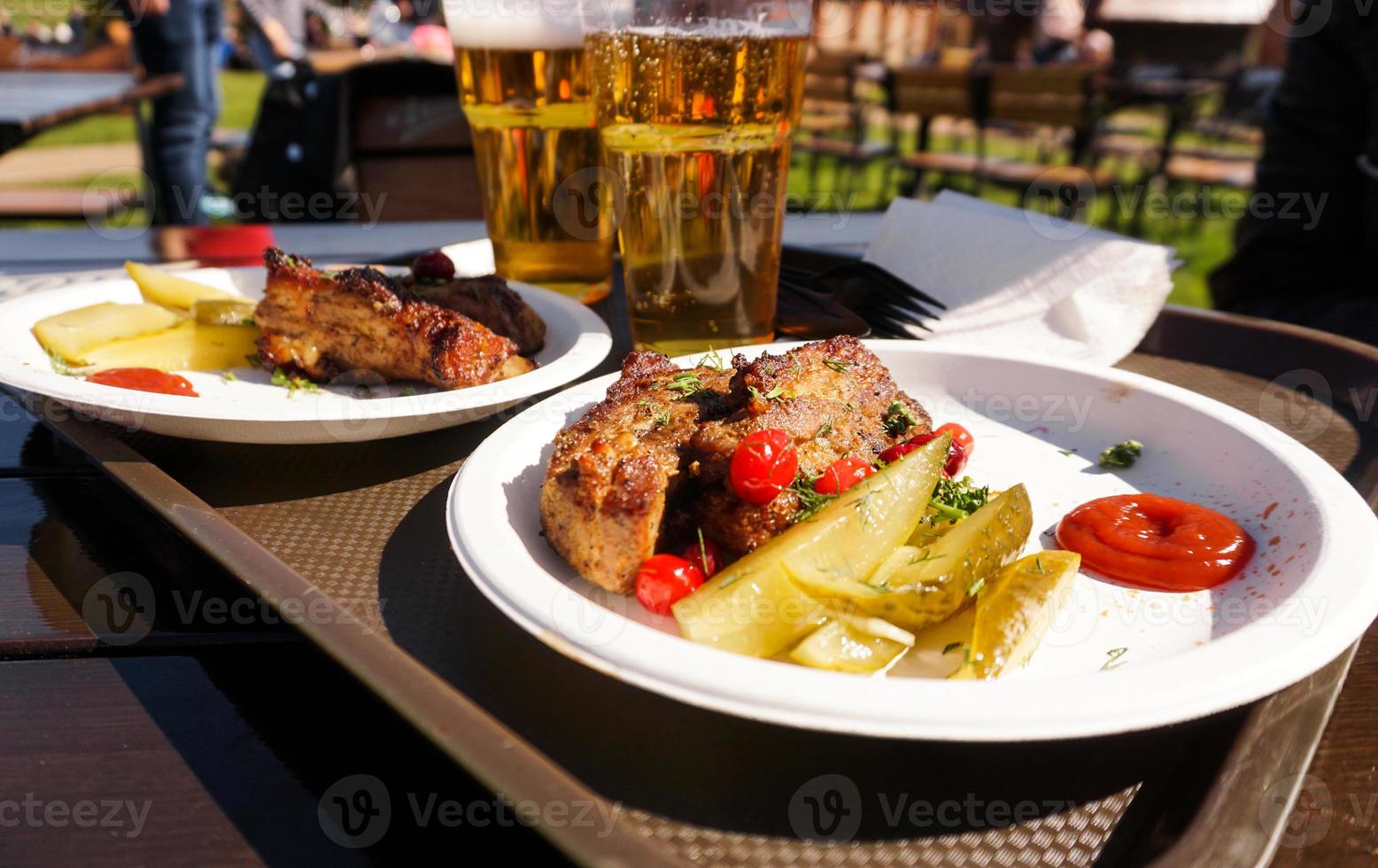 varkensribbetjes op een dienblad en light bier. straatvoedsel. festival eten foto