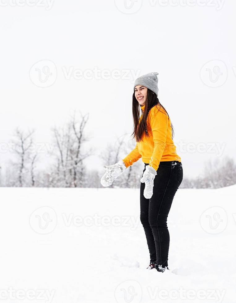 jonge brunette vrouw spelen met sneeuw in park foto