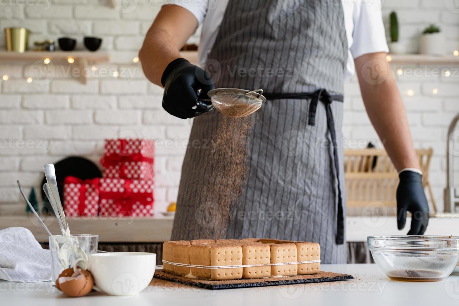 chef-kok kookt dessert in de keuken en giet er cacaopoeder op foto