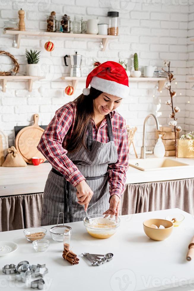 jonge latijnse vrouw die deeg in de keuken mengt foto