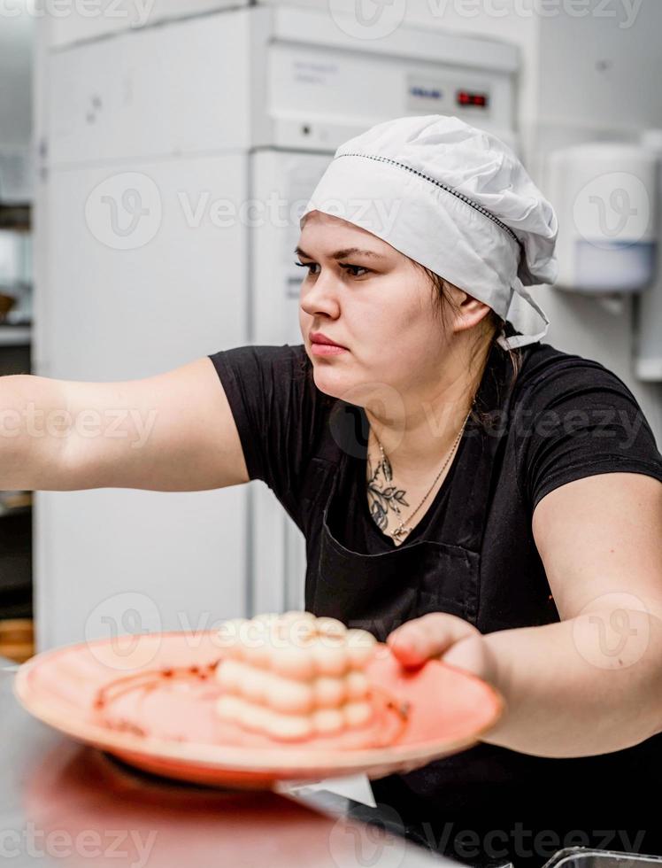 vrouwelijke chef-kok die een dessert serveert in de pizzeria-keuken foto