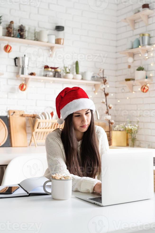 vrouw aan het chatten met vrienden met behulp van haar laptop in de keuken foto