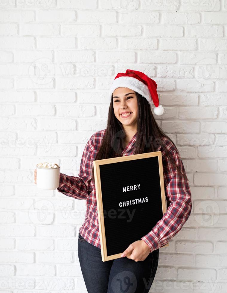 vrouw in kerstmuts met zwarte letterbord foto