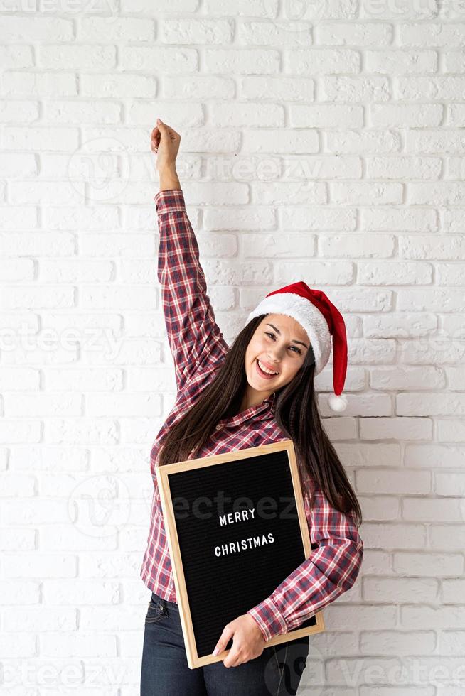 vrouw in kerstmuts met zwarte letterbord foto