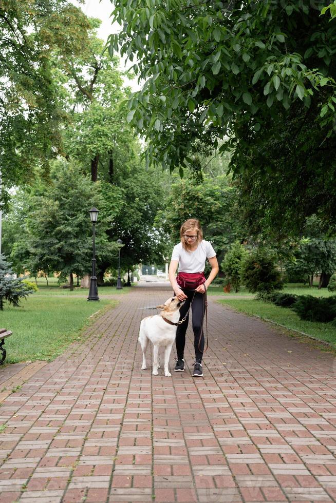 jonge vrouw die haar hond opleidt in een park foto