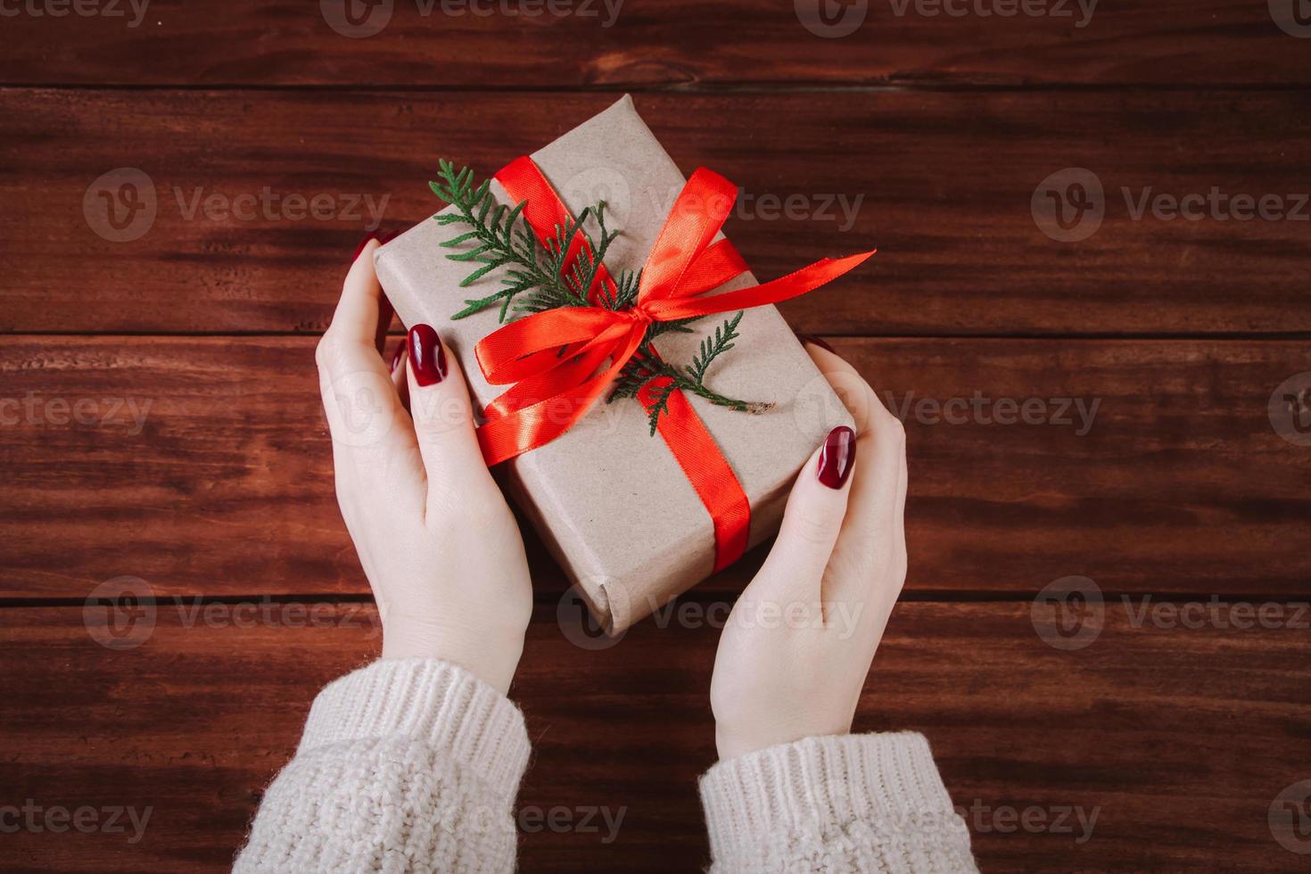 handen houden mooie geschenkdoos op houten achtergrond. foto