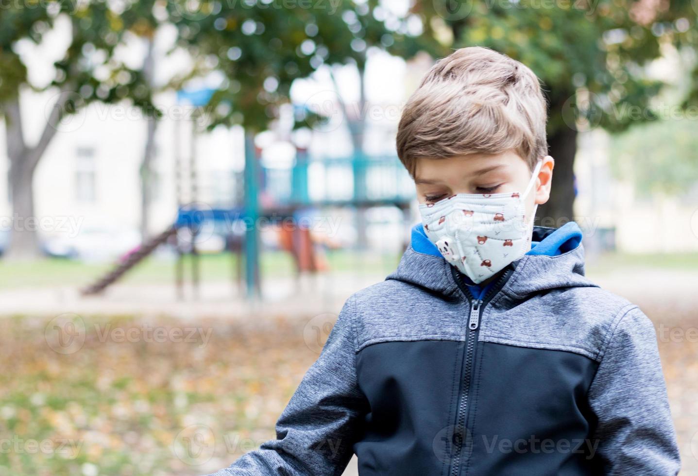 kleine jongen voelt zich eenzaam op de speelplaats tijdens een pandemie van het coronavirus. foto