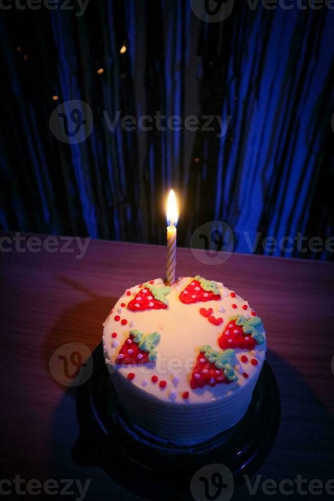 verjaardag taart met hagelslag aardbei en een kaarsen Aan een blauw achtergrond foto
