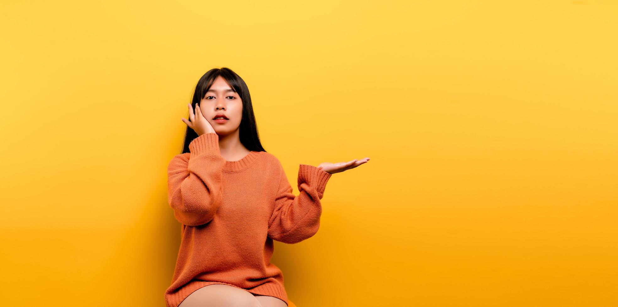 Aziatisch meisje mooi gekleed in een oranje vrijetijdskleding op gele achtergrond foto