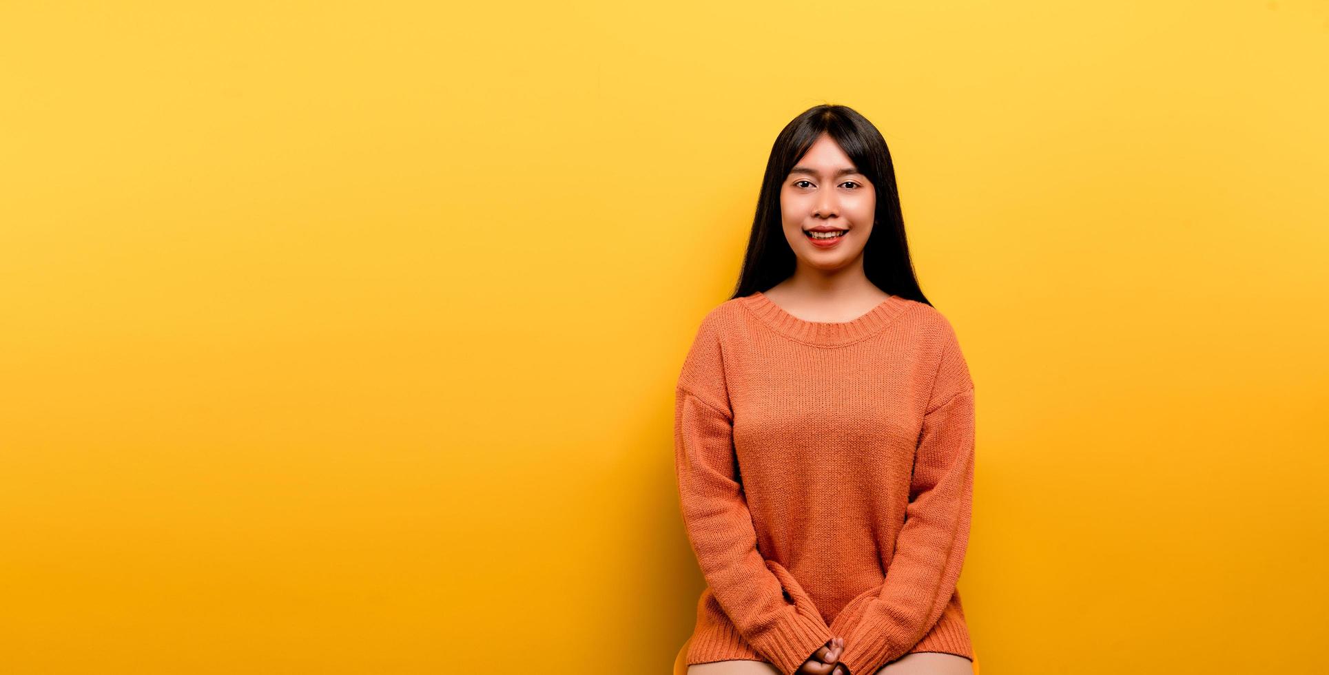 Aziatisch meisje mooi gekleed in een oranje vrijetijdskleding op gele achtergrond foto