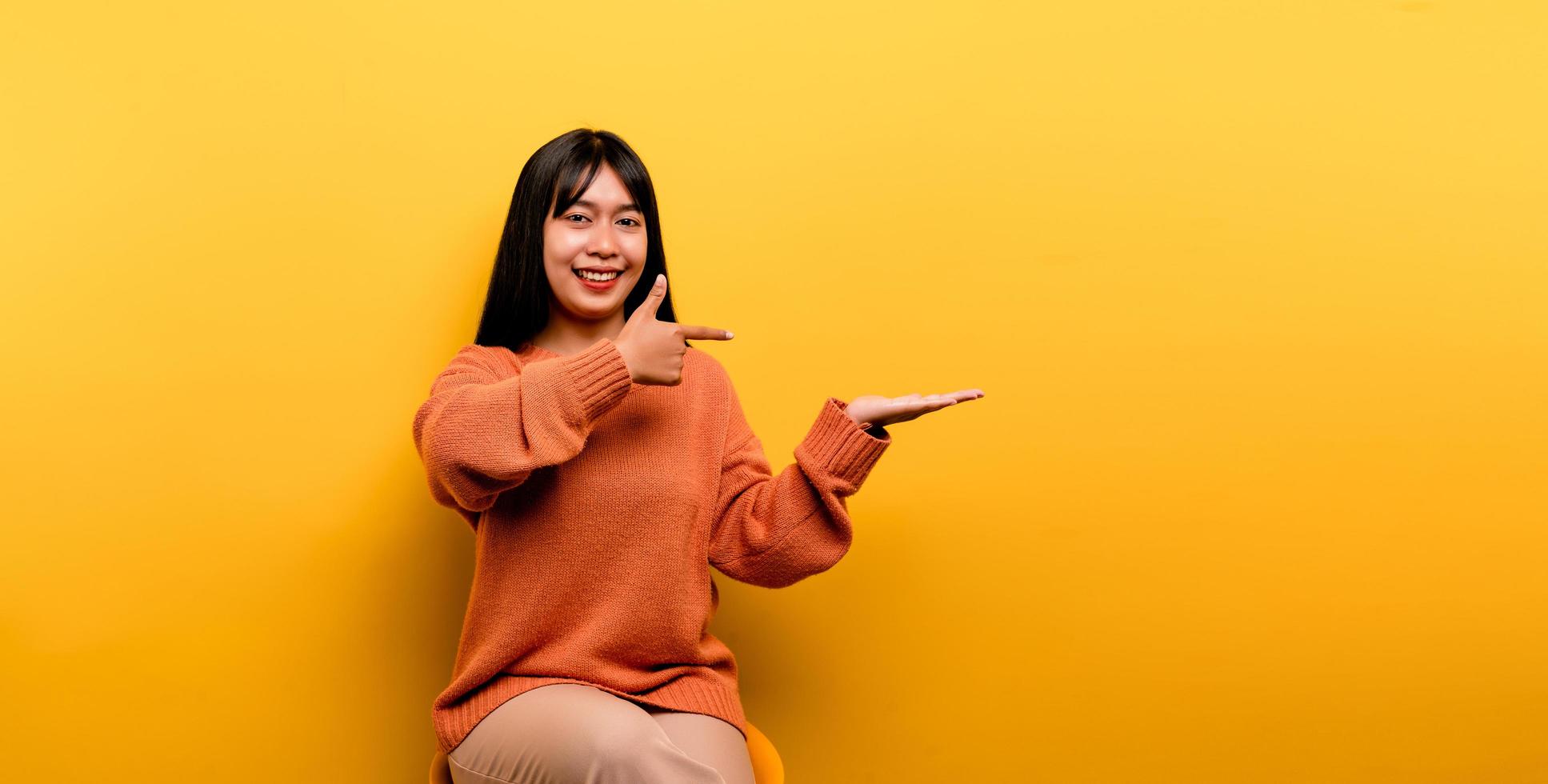 Aziatisch meisje mooi gekleed in een oranje vrijetijdskleding op gele achtergrond foto