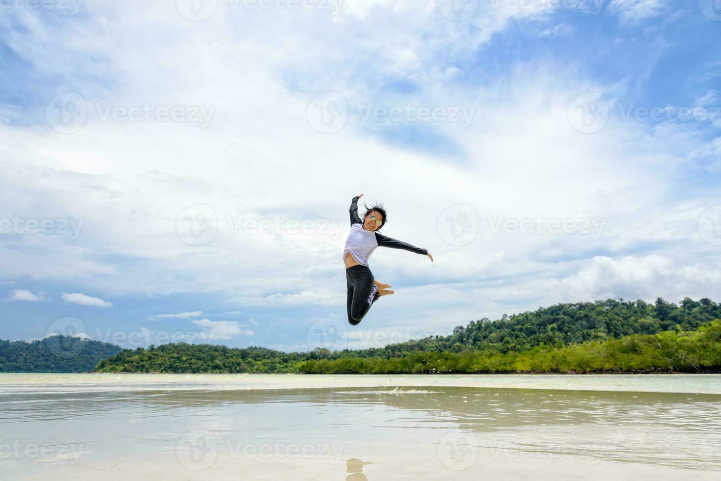 gelukkig Aziatisch vrouw jumping pret Aan de strand foto