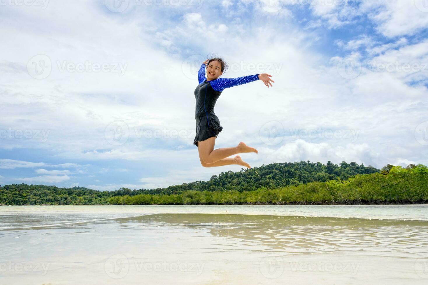 gelukkig Aziatisch tiener meisje jumping pret Aan de strand foto