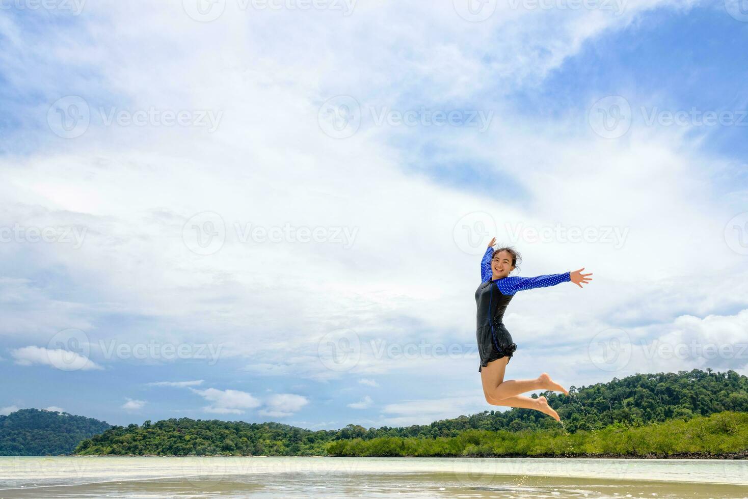 gelukkig Aziatisch tiener meisje jumping pret Aan de strand foto