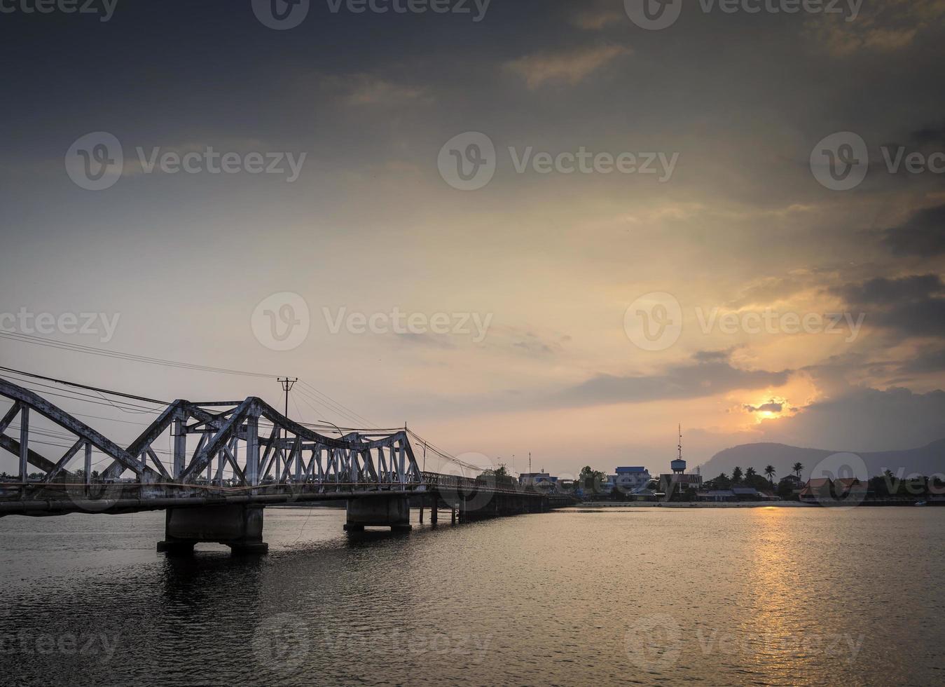 mijlpaal oude brug en rivier bij zonsondergang in kampot cambodja foto