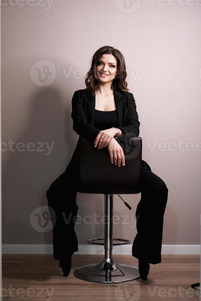 jonge vrouw zittend in een stoel op een grijze achtergrond foto