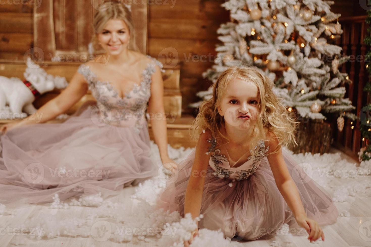 moeder en haar dochter in roze jurken bij de kerstversiering foto