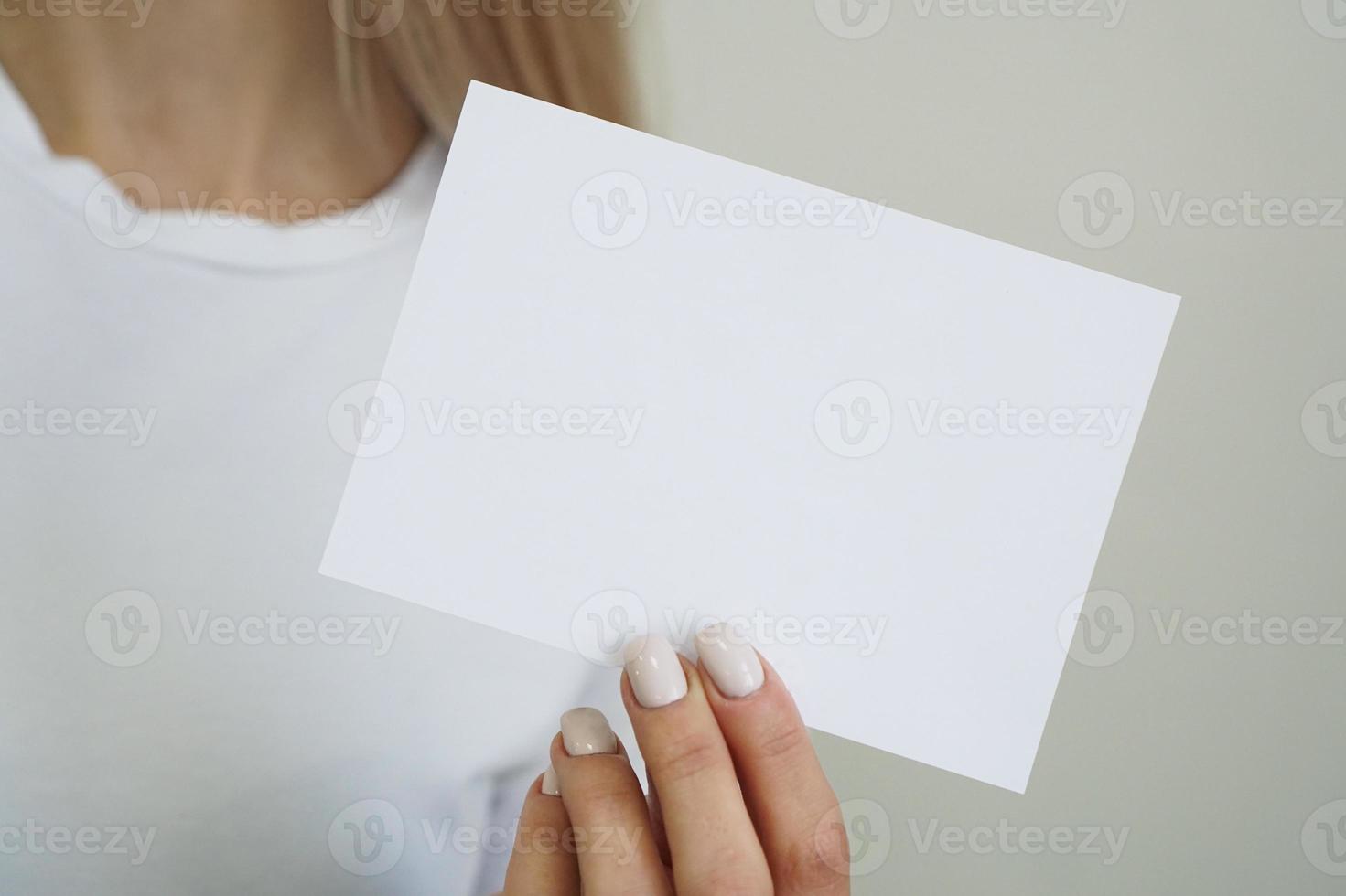 vrouw in wit t-shirt houdt wit blanco vel papier in de hand foto