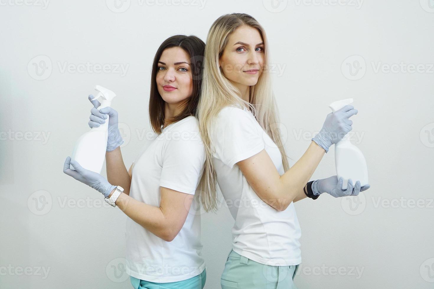 twee vrouwen houden een spuitfles vast - antiseptisch of wasmiddel zoals geweren foto