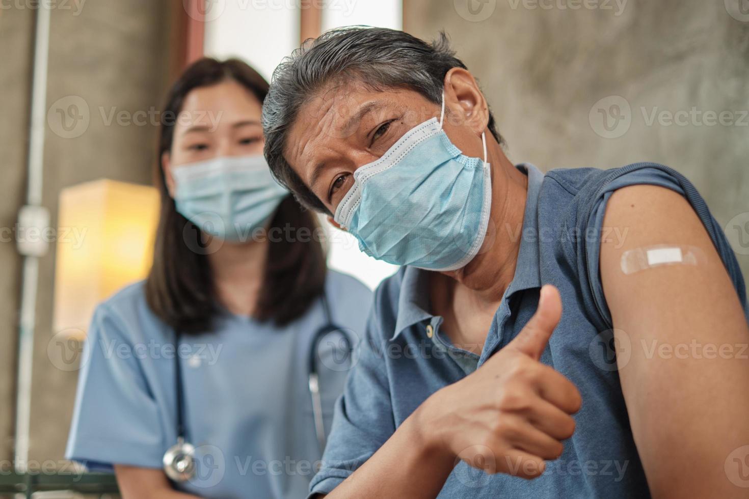 oudere patiënt met gezichtsmasker duim omhoog bij vaccinatie. foto