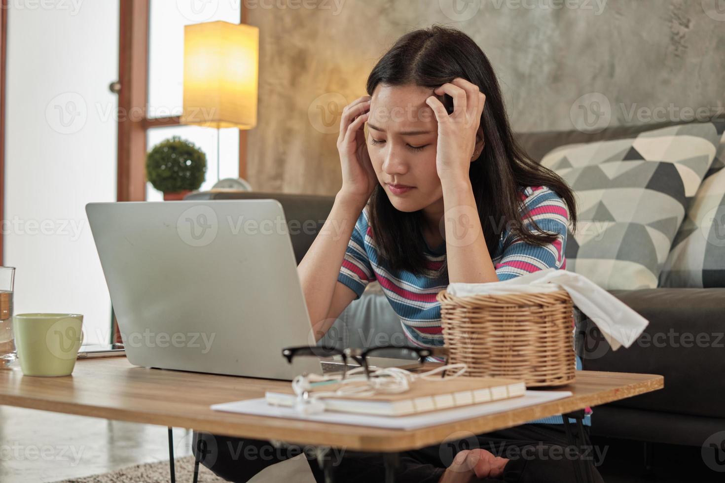 aziatische vrouw die thuis werkt is gestrest en hoofdpijn. foto