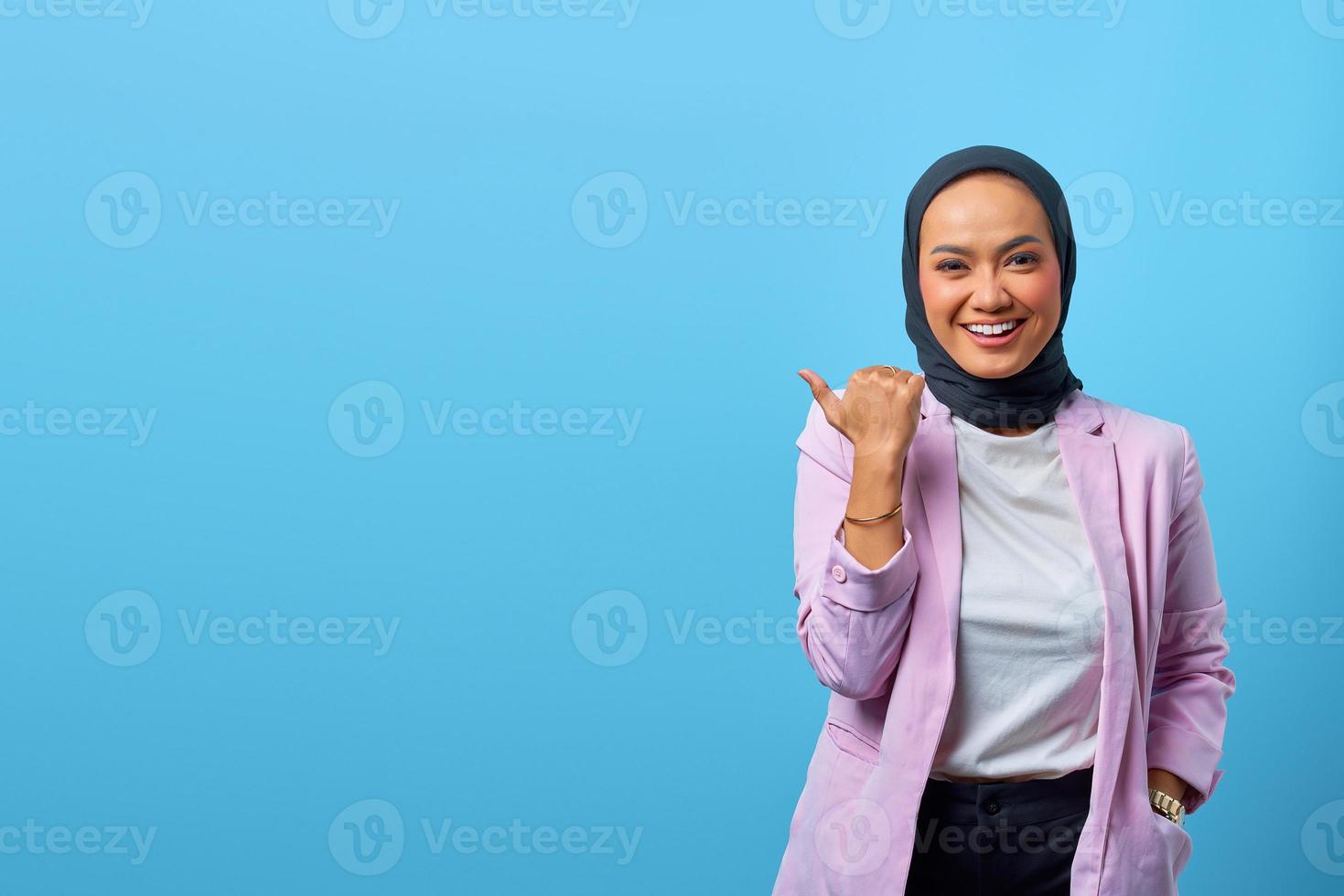 vrolijke aziatische vrouw die met de vingers wijst naar lege ruimte foto