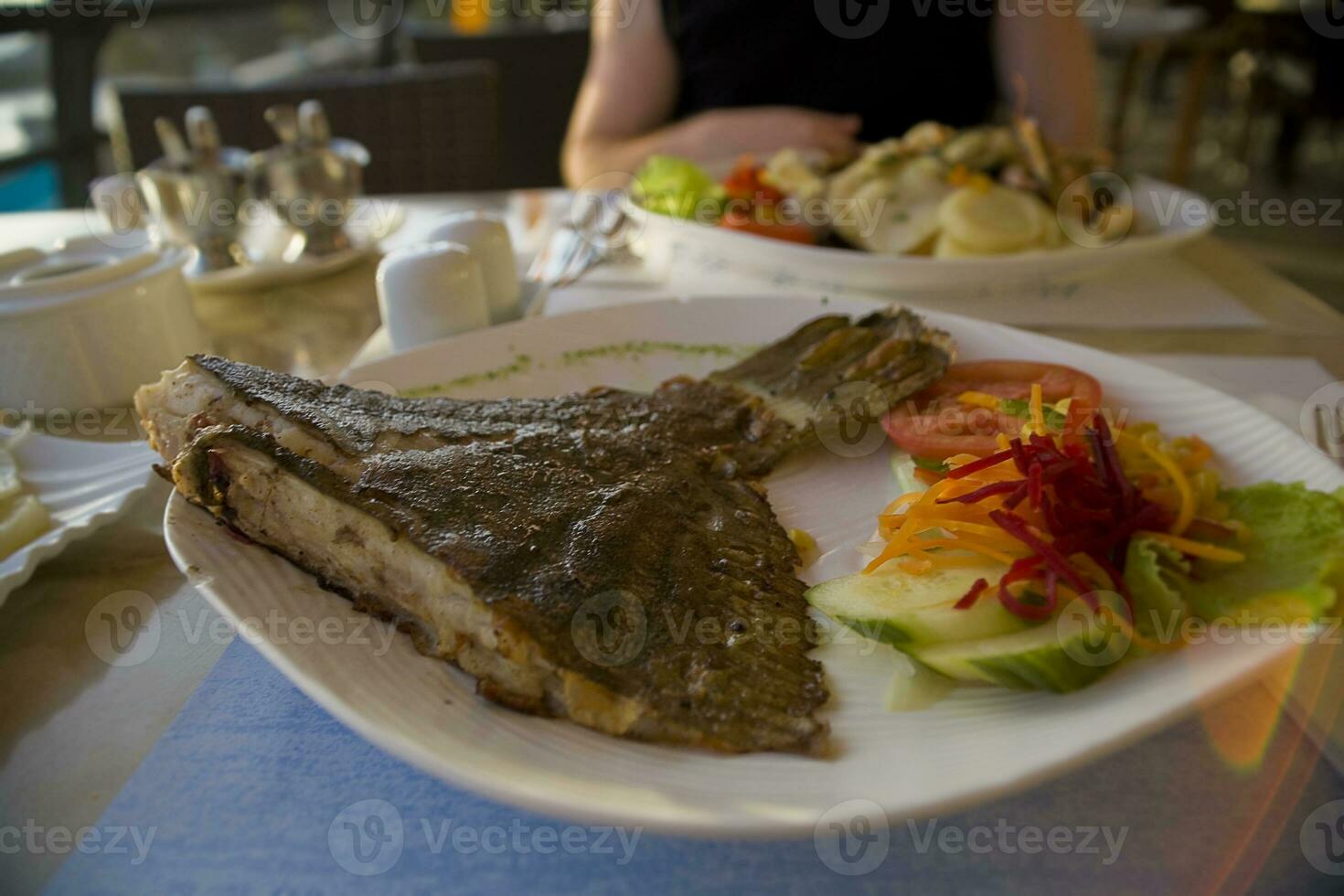 gebakken voor de helft van een groot vis geserveerd Aan een wit bord met groenten in een restaurant foto